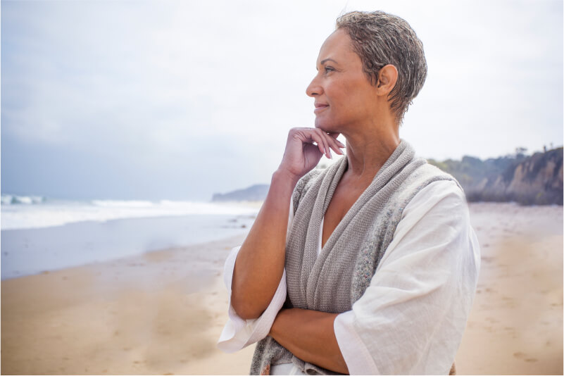 Relaxed woman on the beach looking thoughtfully at the ocean.