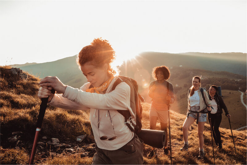 Four woman looking relaxed while hiking up a mountain at sunrise.