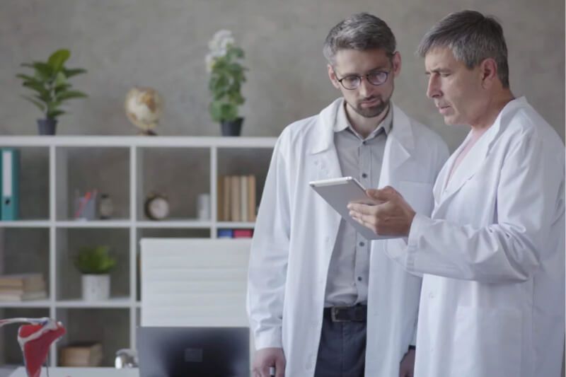 Two male doctors looking at a DTx program on a tablet computer.