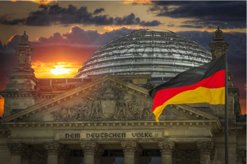 the german flag waving in front of the german reichstag building