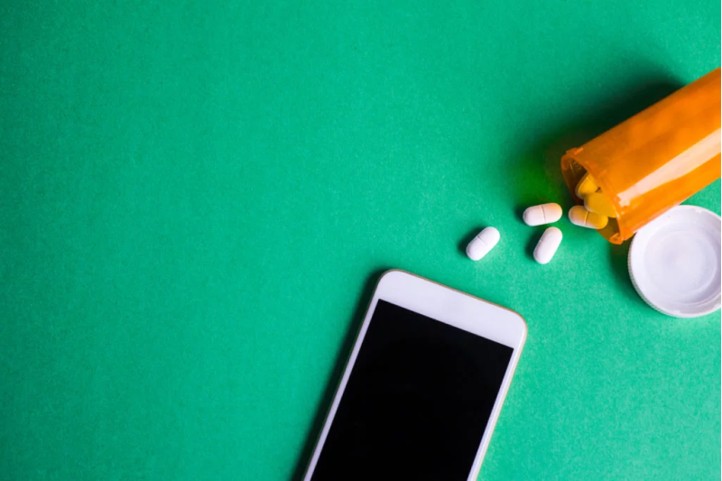 a smartphone next to a bottle of medication