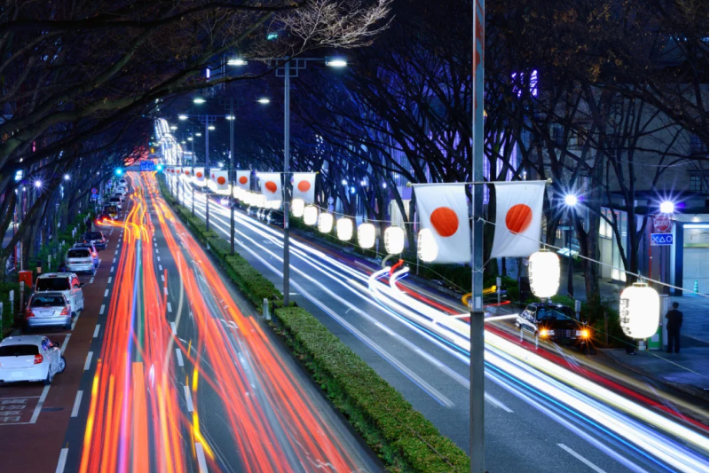 a highway at night with the japanese flag hanging in the street