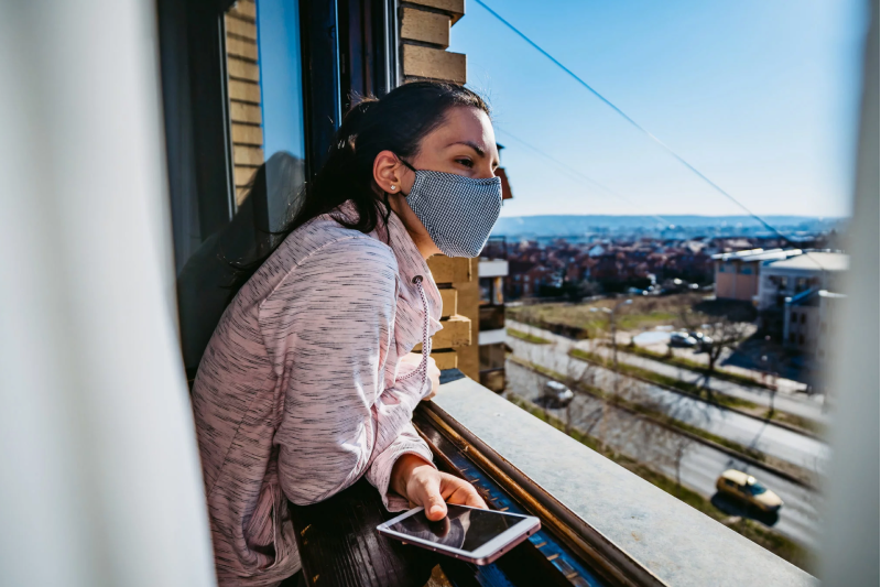 woman wearing a face mask leaning out of a window