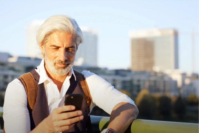 a man looking at a smartphone with a city skyline in the background